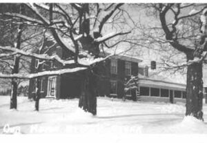 An old brick farm house surrounded by trees and snow